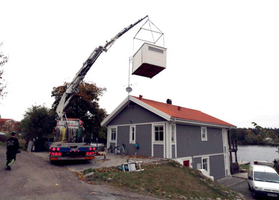 Kranbil som lyfter bastustuga på plats