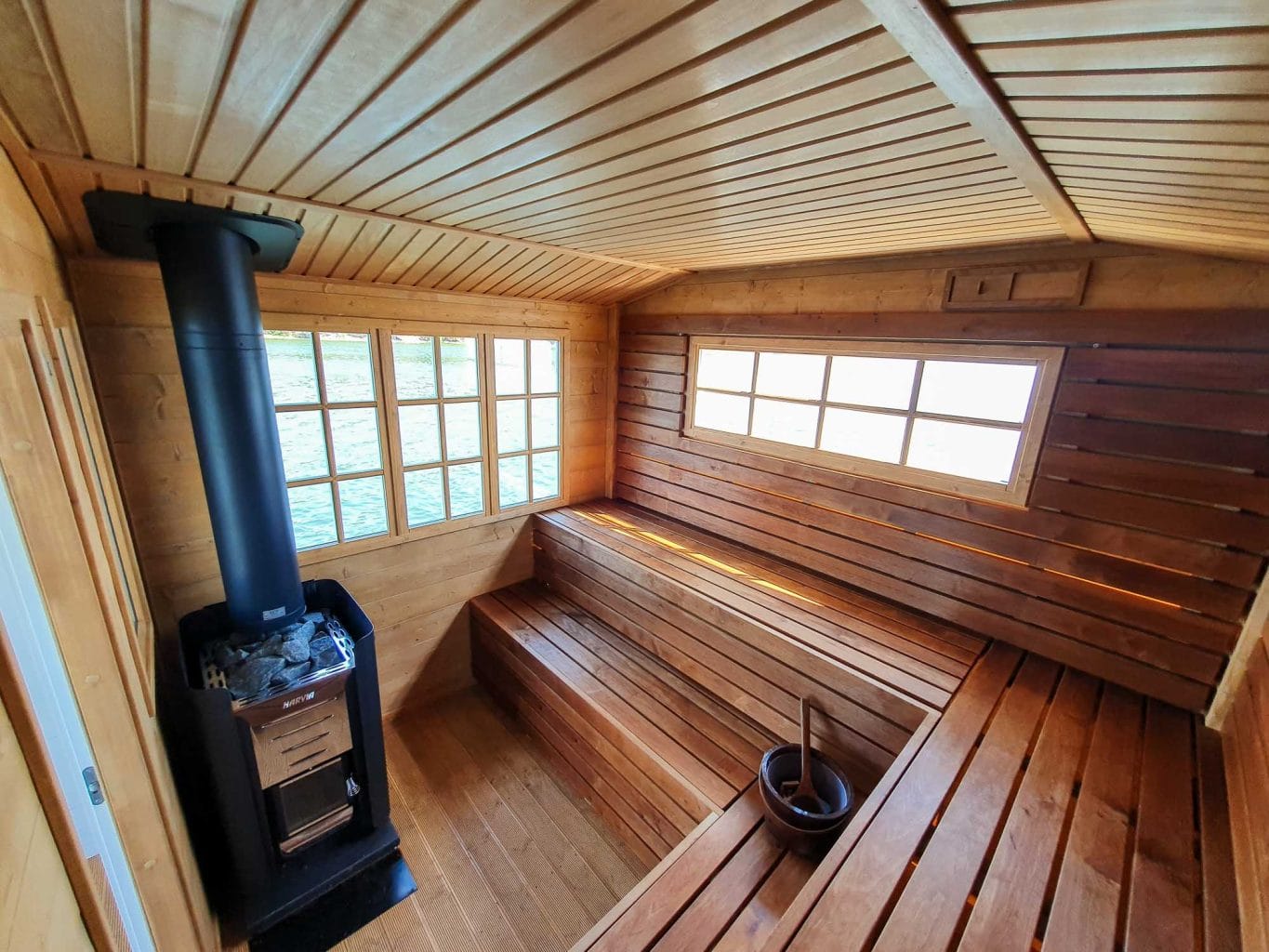 Interior of a CE-certified sauna boat from Marinbastun – wood-burning stove and wooden benches with a view of the water
